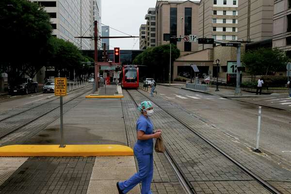 A woman uses the crosswalk on Dryden Road in the Medical Center on Monday, June 22, 2020, in Houston. Texas Medical Center executives and Harris County health officials predict that as COVID-19 cases and hospitalizations continue to rise, the Houston area will effectively return to stay-at-home status as many businesses close due to sick employees.
