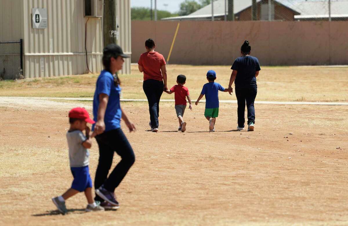 Immigrants seeking asylum hold hands as they walk across the South Texas Family Residential Center in Dilley last year.  (AP Photo/Eric Gay)