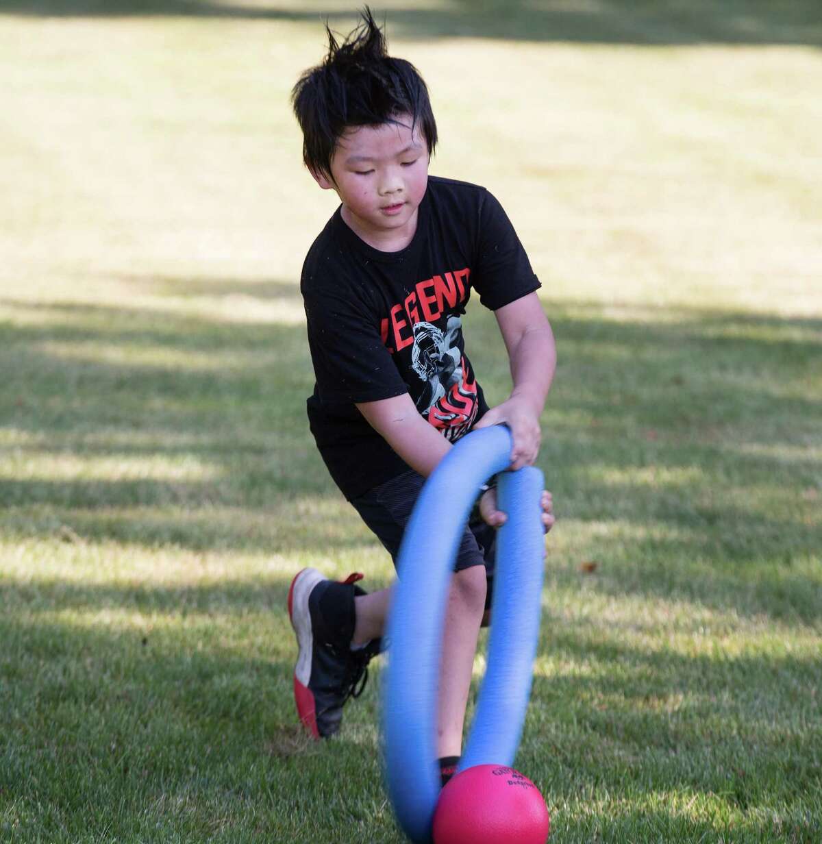 Max Lee hits a ball during a game of noodle hockey on opening day of Camp Looper and Cool Tots.