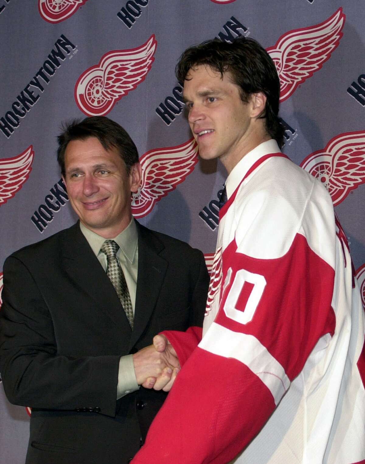 The Detroit Red Wings' newest acquisition, Luc Robitaille, right, shakes hands with general manager Ken Holland during a news conference in Detroit, Thursday, July 5, 2001. Robitaille, a 35-year-old left wing, on Monday agreed to terms with the Red Wings on a two-year contract. He spurned Los Angeles' offer of one year at a reduced salary to stay with the Kings.