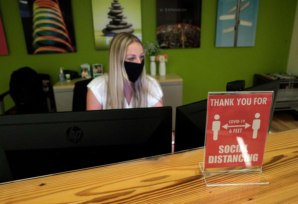 A sign showing the requirement to socially distance in the office sits on the desk of Taylor Mills, administrative assistant at the Armanino offices at Bishop Ranch in San Ramon, Calif., on Tuesday, June 16, 2020. The massive Bishop Ranch office and retail complex in San Ramon has started reopening. Armanino, an accounting firm that is planning to welcome back more office workers, Fieldwork, a brewpub doing outdoor dining, and Heller Jewelers, which recently opened in the center are businesses that are seeing strong foot traffic.