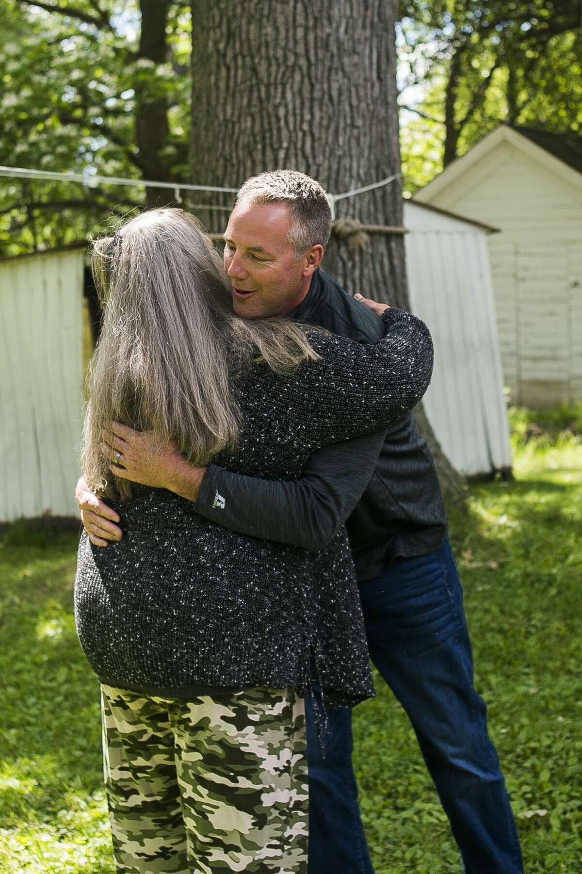 Penny Tyler of Sanford, left, hugs David Dennis, owner of Great Lakes Homes in Freeland, right, after Dennis told her Wednesday, June 24, 2020 that the company will build Tyler a new home at no cost to her on the same site of her family home, which was devastated by the flood. The Islamic Center of Midland and Midland Area Interfaith Friends will furnish the home. (Katy Kildee/kkildee@mdn.net)