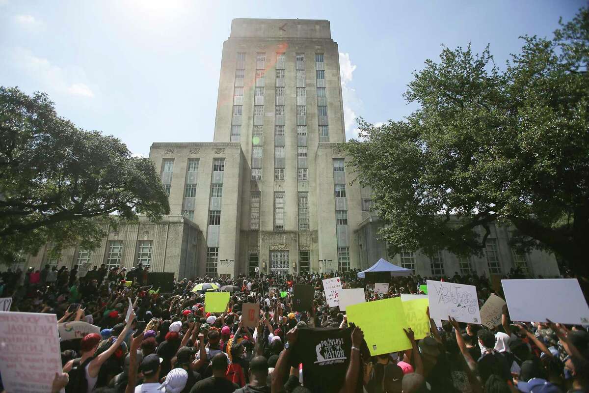 People hold up signs in front of Houston City Hall as they join George Floyd’s family in a march on Tuesday, June 2, 2020.