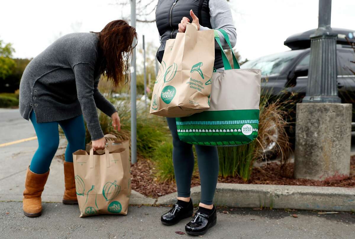 After not being able to use their own bags, Bertha Iavorone and her daughter, Rebeca, leave with store provided paper bags after shopping at Whole Foods in Mill Valley, Calif., on Monday, April 6, 2020.