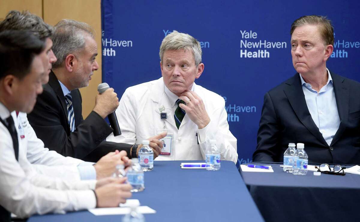 Dr. Michael Ivy (center), Deputy Chief Officer of Yale New Haven Health System, and Governor Ned Lamont (right) listen to State Senator Saud Anwar (left) speak at a roundtable discussion on the impact of the coronavirus at Bridgeport Hospital's Milford Campus on February 28, 2020.