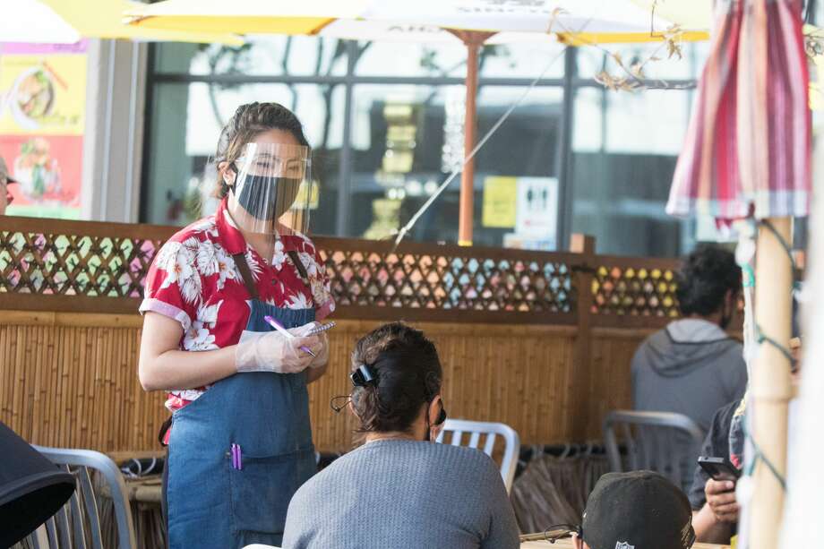 Waitress Jariya Namwaan takes a customer's orders while working a shift at Farmhouse Kitchen in Oakland, Calif. on June 23, 2020. The restaurant recently re-opened to customers for outdoor dine-in service. Photo: Douglas Zimmerman/SFGATE / SFGATE