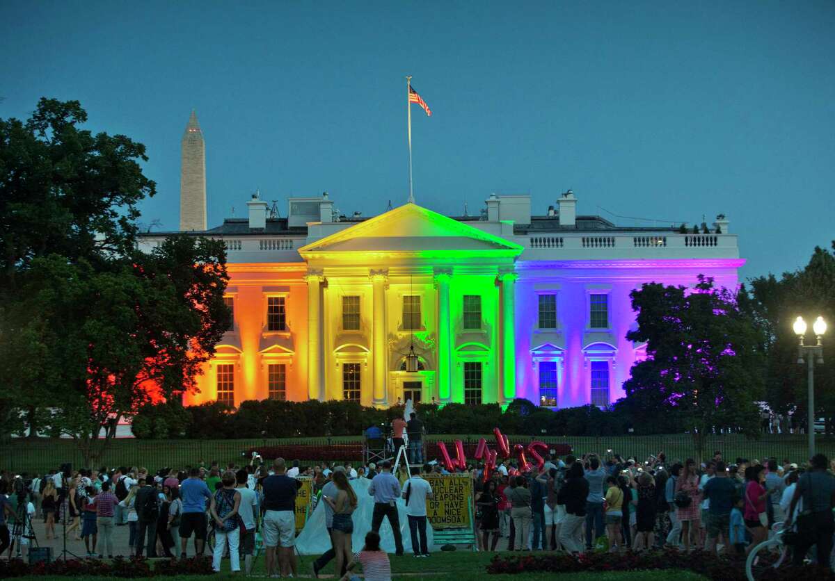 In this Friday, June 26, 2015 file photo, people gather in Lafayette Park to see the White House illuminated with rainbow colors in commemoration of the Supreme Court's ruling to legalize same-sex marriage in Washington. The Trump administration Friday, June 12, 2020, finalized a regulation that overturns Obama-era protections for transgender people against sex discrimination in health care.