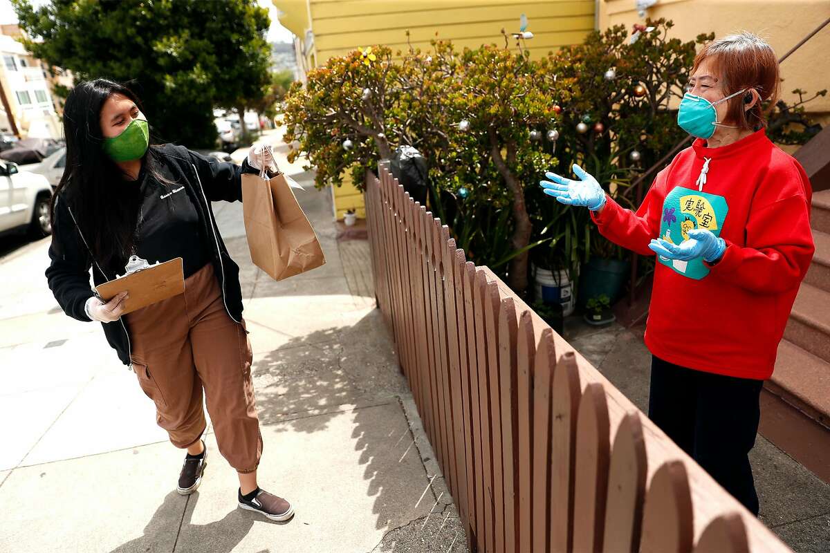Angela Santelices hands a food bag to Maria Chu as part of Filipino Community Center food delivery program in San Francisco, Calif., on Thursday, June 11, 2020.