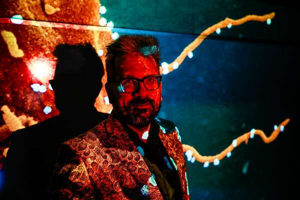 Nevan Krogan, a molecular biologist at UCSF, with an image showing the coronavirus as it attaches to a cell and branches out.