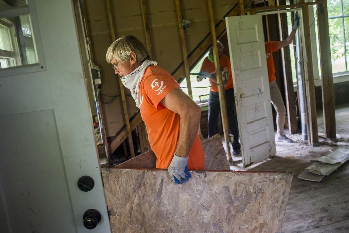 Kurt Weinberger, a volunteer with Samaritan's Purse, removes sheets of plywood from a home on E. Pine River Road as his crew wraps up their efforts Friday, June 26, 2020 in Midland. Over the course of five weeks, the organization has employed the assistance of 1,500 volunteers to aid over 300 area families with flood relief. (Katy Kildee/kkildee@mdn.net)