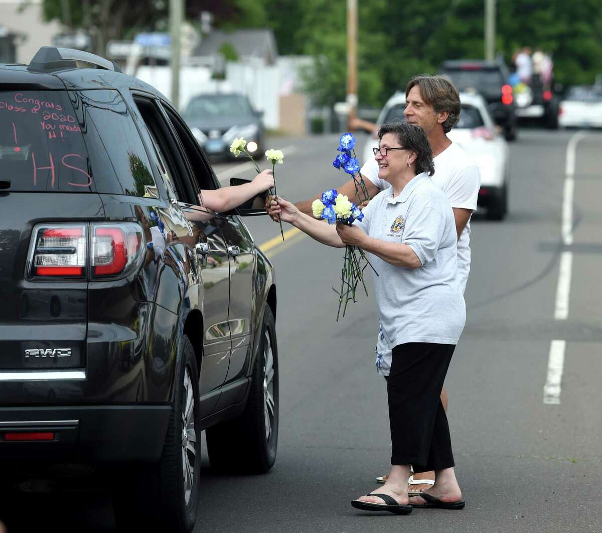 Annarose Russo (center) and Michael Perrelli (background) hand out carnations to East Haven High School grads in a motorcade starting out at Coe Avenue and ending at East Haven High School on June 28, 2020.