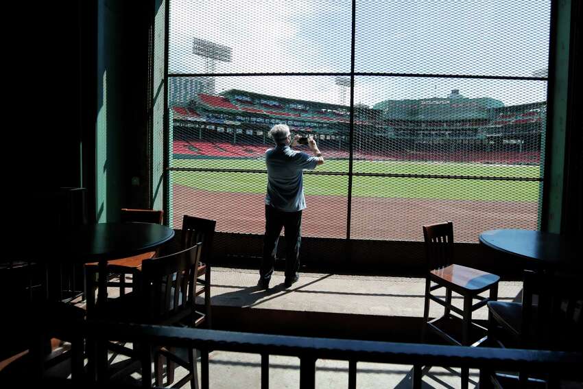 In this June 25, 2020, photo, a reporter photographs the view of the baseball field at Fenway Park from the Bleacher Bar in Boston. Tucked under the center field seats at Fenway Park, down some stairs from Lansdowne Street in an area previously used as the visiting teama€™s batting cage, is a sports bar that is preparing to reopen from the coronavirus shutdown. If Major League Baseballa€™s plans remain on schedule, it may be one of the few places fans will be able to watch a game in person this season. (AP Photo/Elise Amendola)