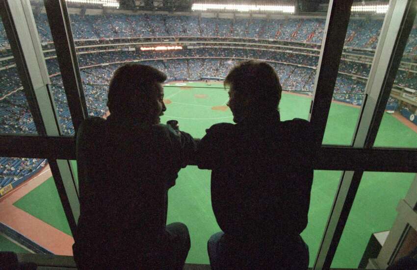 FILE - In this Oct. 22, 1992, file photo, spectators look out at the field of the SkyDome in Toronto, from a window of the SkyDome Hotel before Game 5 of the World Series between the Toronto Blue Jays and the Atlanta Braves. This week, Major League Baseball players and owners reached an agreement to play an abbreviated, 60-game season that would start July 23 or 24 in teamsa€™ home ballparks. But the seats will be empty. Instead, fans hoping to see a game in person will be have to settle for pressing their faces up against hotel windows, squinting through metal grates or climb to rooftops when baseball returns this month in otherwise empty stadiums. (AP Photo/Rusty Kennedy, File)
