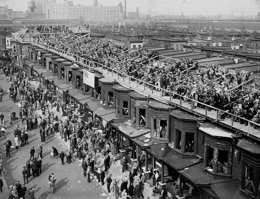 FILE - This October 1929 file photo shows baseball fans on the roofs of row houses overlooking Shibe Park to watch the Philadelphia Athletics play against the Chicago Cubs for $5.00, in Philadelphia. The windows are taken out of the second floor window frames. This week, Major League Baseball players and owners reached an agreement to play an abbreviated, 60-game season that would start July 23 or 24 in teamsa€™ home ballparks. But the seats will be empty. Instead, fans hoping to see a game in person will be have to settle for pressing their faces up against hotel windows, squinting through metal grates or climb to rooftops when baseball returns this month in otherwise empty stadiums. (AP Photo/File)