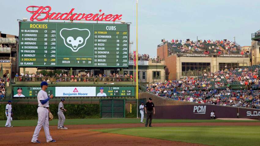 FILE - In this July 28, 2015, file photo, fans at a Wrigley Rooftops' building down the right-field line outside Wrigley Field watch players during the first inning of a baseball game between the Colorado Rockies and Chicago Cubs in Chicago. This week, Major League Baseball players and owners reached an agreement to play an abbreviated, 60-game season that would start July 23 or 24 in teamsa€™ home ballparks. But the seats will be empty. Instead, fans hoping to see a game in person will be have to settle for pressing their faces up against hotel windows, squinting through metal grates or climb to rooftops when baseball returns this month in otherwise empty stadiums. (AP Photo/Andrew A. Nelles, File)