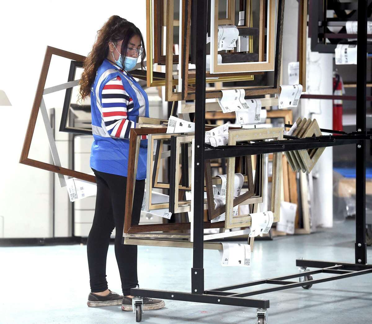 Yaneysa Zepeda moves completed custom frames to a rack at the newly opened Art To Frames factory in the Fair Haven section of New Haven on June 29, 2020.