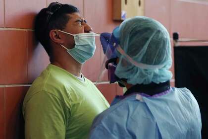 Oscar Cruz, 32, left, gets a free COVID-19 test at Burbank High School.