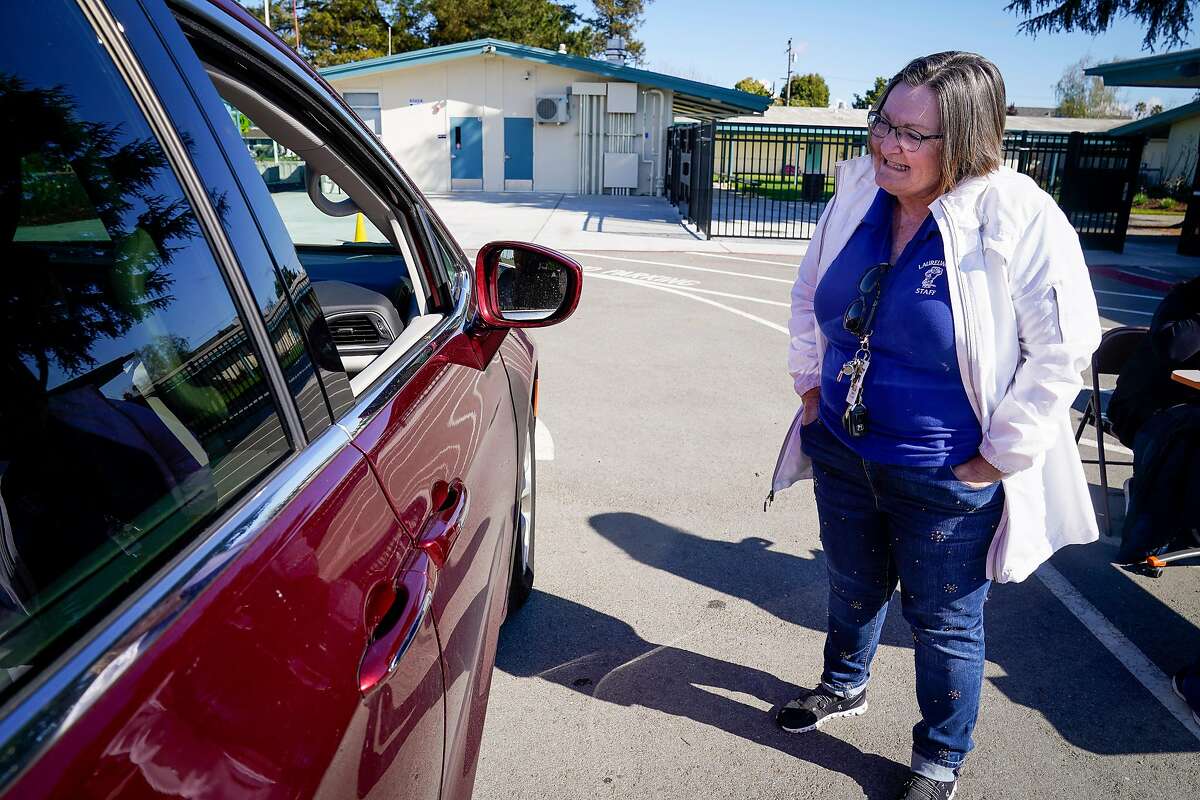 Lori Roger, principal at Laurelwood Elementary school, talks to a parent they pick up a Chromebook at a drive through so students can use them at home to attend online classes in the Santa Clara Unified District during the coronavirus outbreak on Thursday, March 26, 2020, in Santa Clara, Calif.