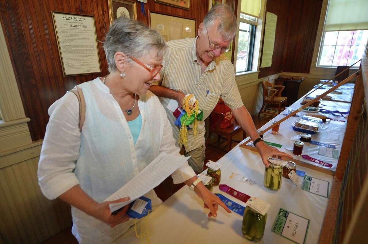 Head Judge Sara Schrager, and Bil Mikulewicz place ribbons on the winners’ entries during judging at the 84th annual Cannon Grange Fair at the Cannon Grange in Wilton, Connecticut, during a previous year. A full night of laughs, free food and entertainment that is titled: “Comedy Night In Wilton,” is scheduled for the community organization, Cannon Grange, on Saturday, July 24, at 8 p.m. Doors for the event will open at 7:30 p.m.