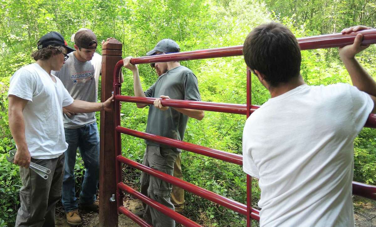 Student volunteers from the New Milford Youth Agency put the finishing touches on a gate to Weantinoge's 80-acre Still Reserve Preserve in New Milford. August 2015