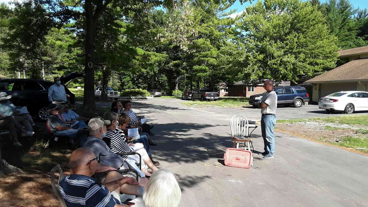 Doug Loose, right, speaks to owners of Village West Condominiums during an outdoor meeting recently, where he presented a proposal to purchase their flooded residences, restore them and rent them to the current owners at a discounted rate. (Dan Chalk/chalk@mdn.net)