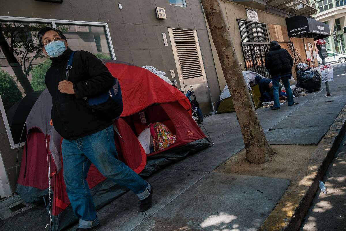 A pedestrian walks past a small tent encampment on the corner of Taylor and Ellis in San Francisco on Tuesday, July 2, 2020.