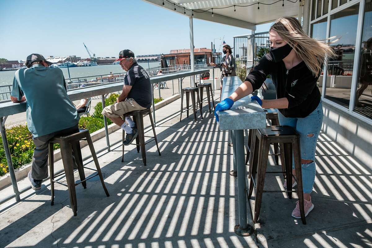 Megan Keeton sterilizes the patio furniture at Mare Island Brewing Taproom in Vallejo on Thursday, July 2, 2020.