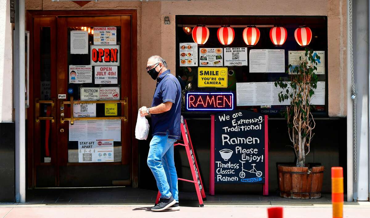 A man wearing a facemask walks past a Ramen restaurant in Los Angeles, California on July 1, 2020, after indoor restaurants, bars and movie theaters across much of California were ordered to close for at least three weeks. - Some Californian restaurants shut their doors Wednesday as new measures to tackle the coronavirus pandemic threaten to scupper US Independence Day plans, with beaches closed, fireworks displays scrapped and family reunions put on hold. Indoor restaurants, bars and movie theaters across much of California were ordered to close for at least three weeks, in a major reversal of the state's reopening process. (Photo by Frederic J. BROWN / AFP) (Photo by FREDERIC J. BROWN/AFP via Getty Images)