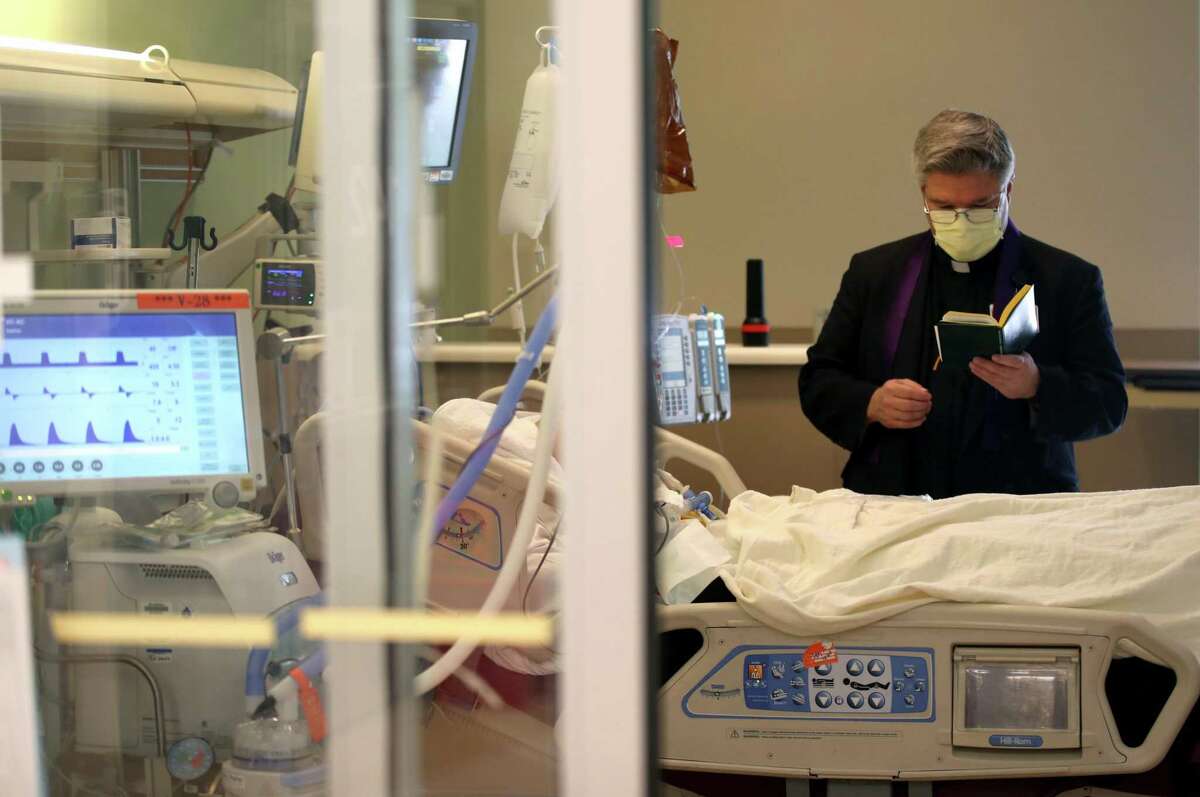 Father Barry O'Toole reads a prayer to a patient in the intensive care unit on May 21 at Regional Medical Center in San Jose.