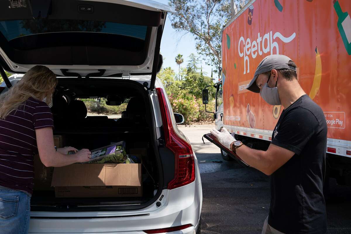 Chelsey Lost, 37, of Livermore, left, picks up a grocery order from Byron Eppler, 35, a customer success specialist with Cheetah food supply, in Pleasanton, Calif., on Tuesday, June 16, 2020.