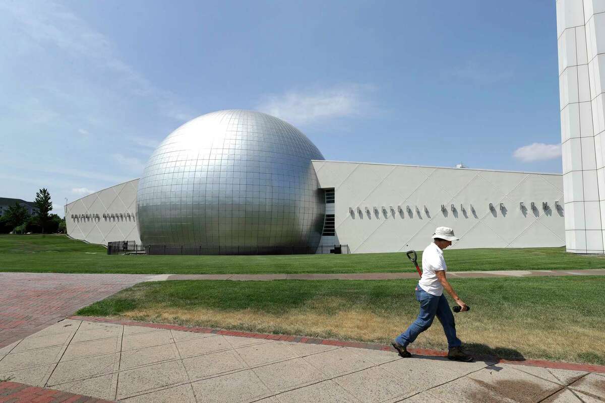 A worker carries a shovel in front of the Naismith Memorial Basketball Hall of Fame in Springfield, Mass., Tuesday, June 23, 3030. The museum is scheduled to reopen in the beginning of July 2020 with a whole new look after a $22 million renovation. (AP Photo/Steven Senne)