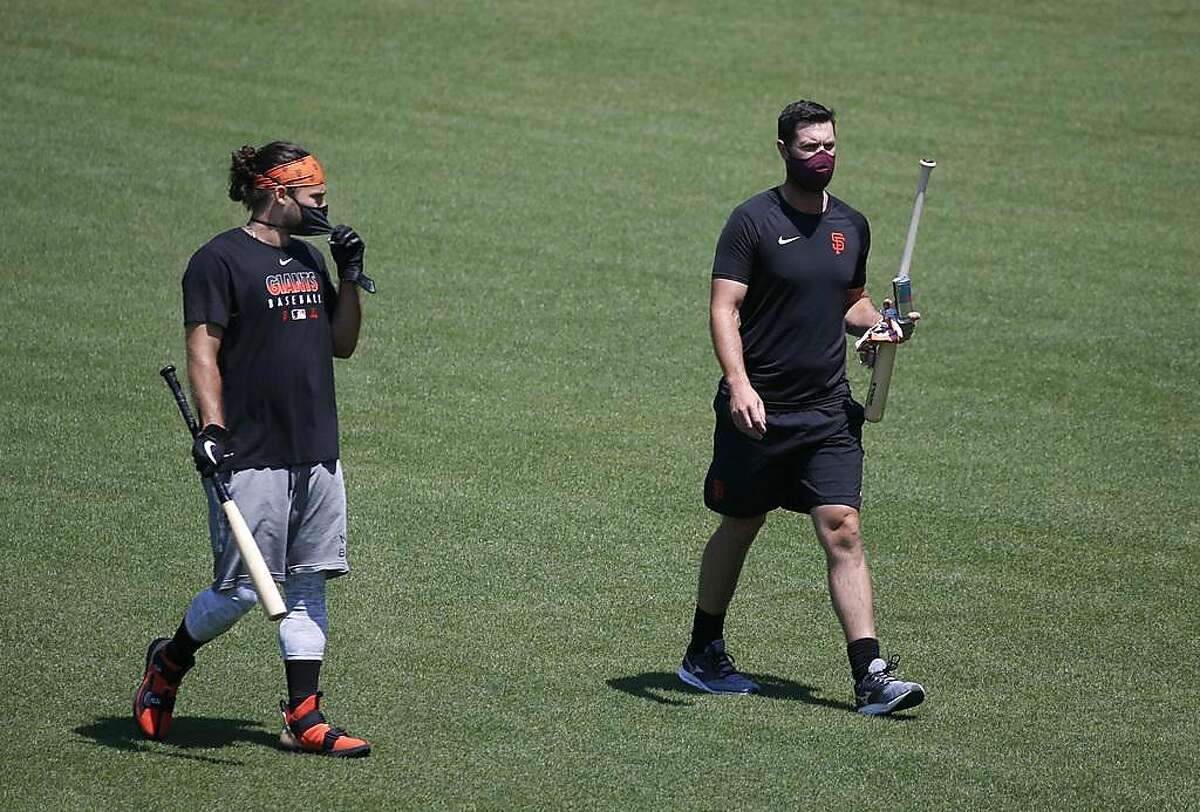 Brandon Crawford and Brandon Belt wear face coverings while walking off the field after the Giants first Spring Training workout during the coronavirus pandemic at Oracle Park San Francisco, Calif. on Friday, July 3, 2020.