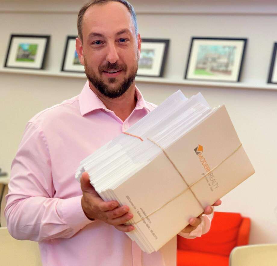 Modern Realty owner Logan Richetti, spokesman and broker for Village West Condominiums, holds the 46 individual contract documents on Friday after the 46 Village West owners unanimously agreed to developer Doug Loose's purchase offer.