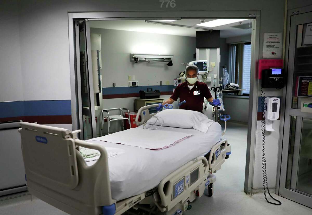 A maintenance worker wheels a bed into a room that is being prepared for a COVID-19 patient at Methodist Hospital.