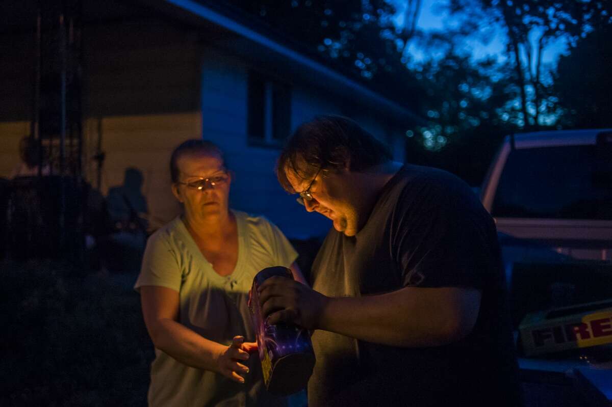Marybeth Coons, left, and Timothy Coons, right, light a firework while celebrating Independence Day Saturday, July 4, 2020 in Midland. (Katy Kildee/kkildee@mdn.net)
