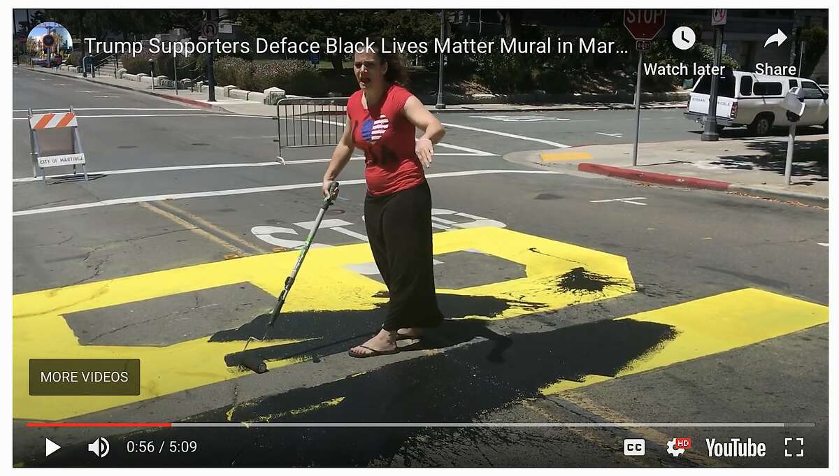 An as-yet unidentified woman paints over a just-finished Black Lives Matter mural painted on the street in front of the Contra Costa County Courthouse in Martinez on Saturday, July 4, 2020. A man with her used his phone to make video of bystanders who challenged their right to paint over the mural.