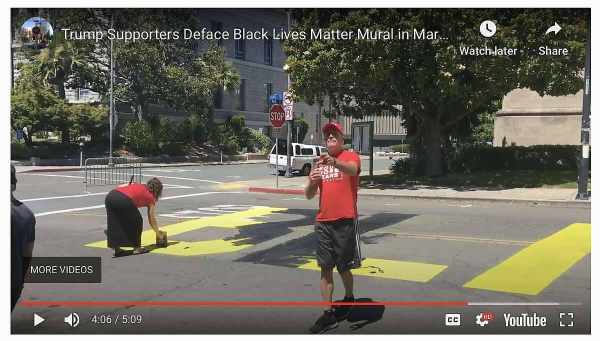 An as-yet unidentified woman paints over a just-finished Black Lives Matter mural painted on the street in front of the Contra Costa County Courthouse in Martinez on Saturday, July 4, 2020. A man with her used his phone to make video of bystanders who challenged their right to paint over the mural.