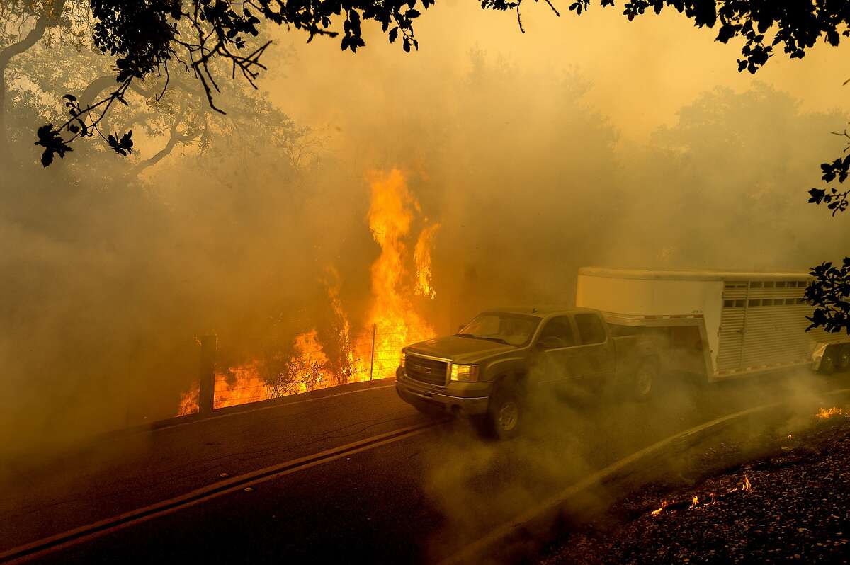 A livestock trailer drives along Canada Road as the Crews Fire burns near Gilroy, Calif., on Sunday, July 5, 2020. (AP Photo/Noah Berger)