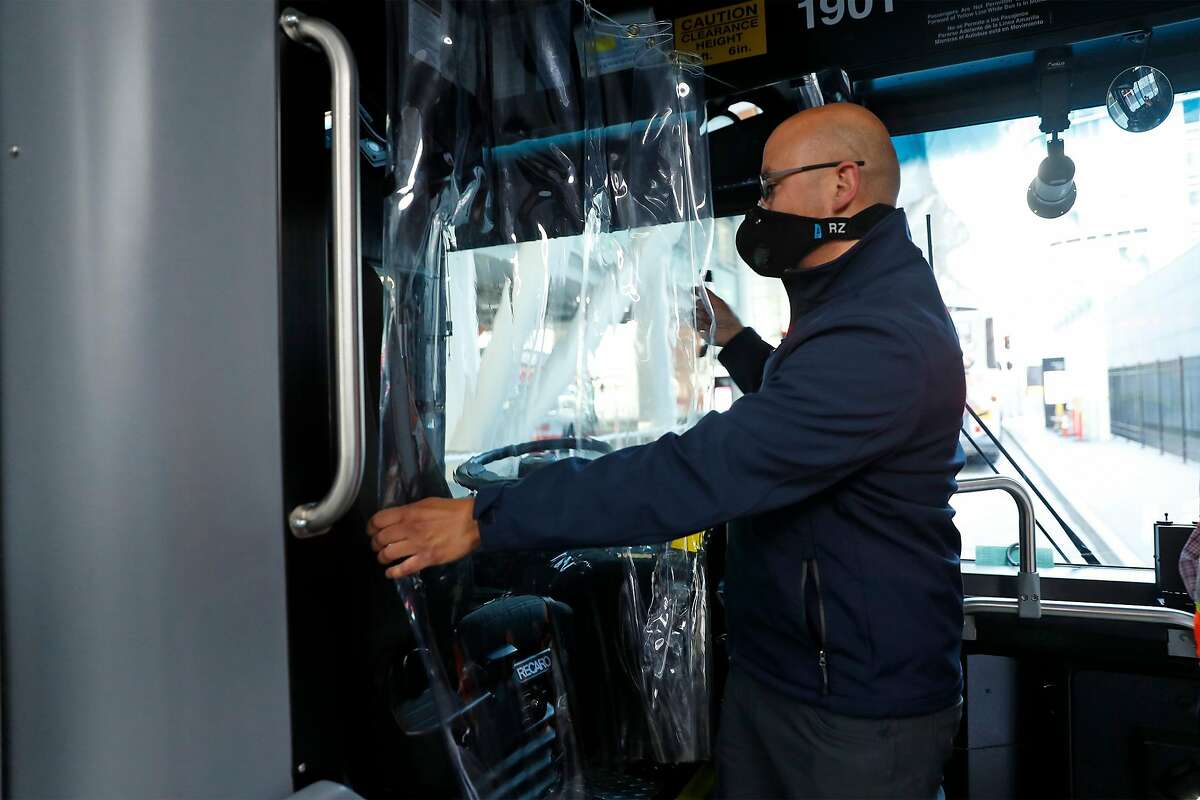 Luis Licea moves a moisture barrier before operating a Golden Gate Transport bus in San Francisco, Calif., on Wednesday, June 24, 2020. People returning to public transportation can expect familiar safety protocols used on recommendations from the CDC. Those include mandatory face coverings for riders and operators, physical distancing markers and limited capacity on all vehicles.