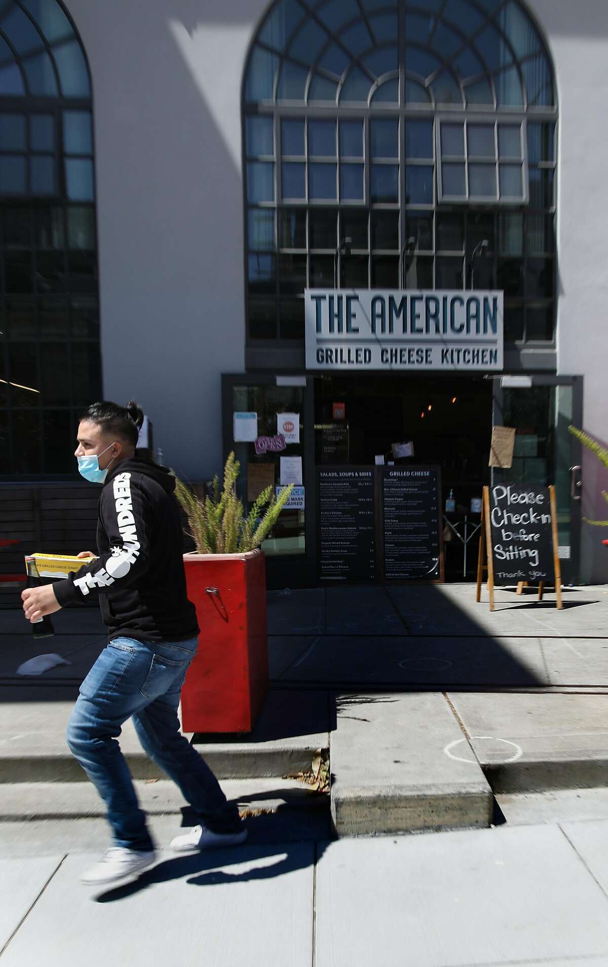 A customer picks up an order at The American Grilled Cheese Kitchen on Tuesday, July 7, 2020, in San Francisco, Calif. Mayor London Breed may announce a change of plans on indoor dining in SF.
