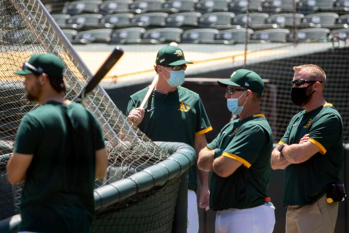 Various coaches sport face masks while participating in an Oakland A's training camp workout at O.Co Coliseum in Oakland, Calif. Tuesday, July 7, 2020. Due to COVID-19, the 2020 MLB season has been postponed with players just beginning to return for warmups and practices while wearing masks and keeping social distance.