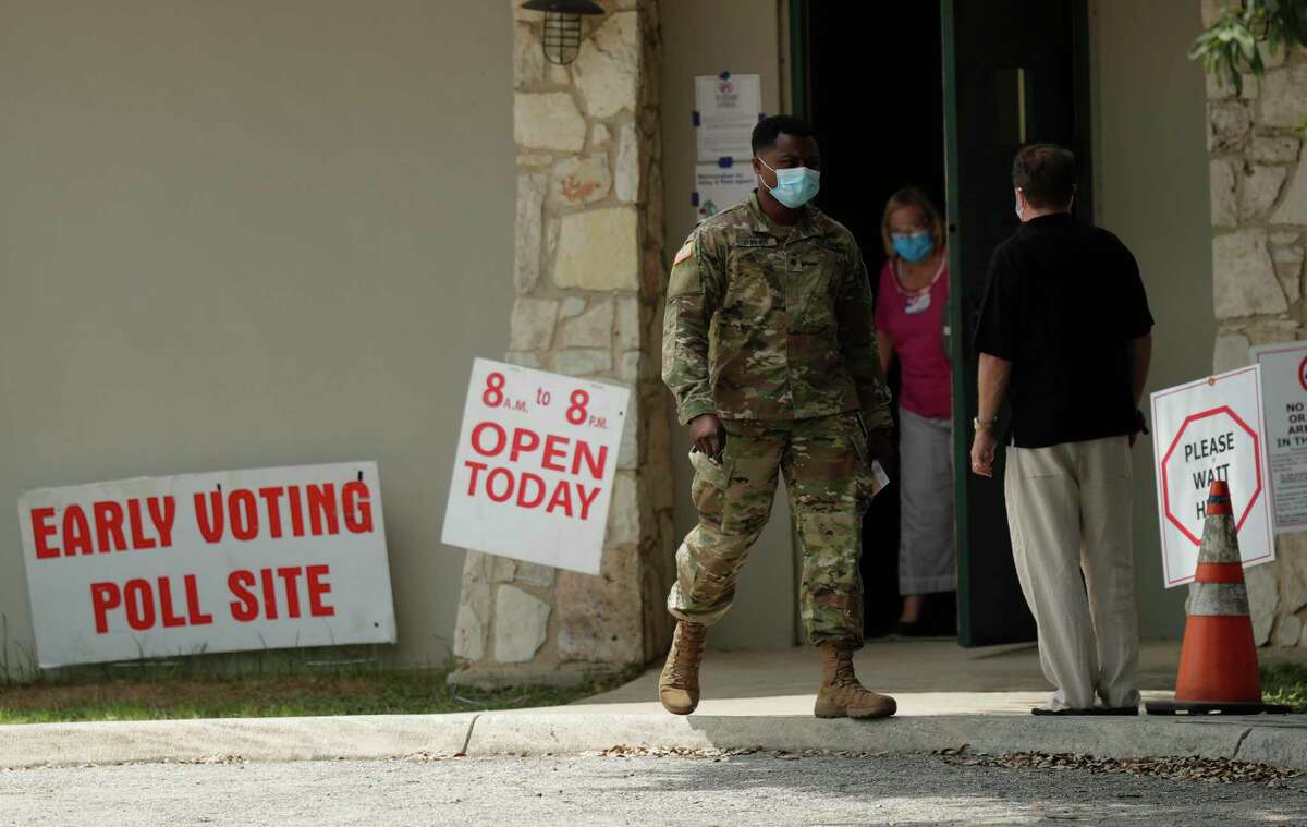 Ellen Ott, center, controls the flow of early voters at a polling site, Tuesday, July 7, 2020, in San Antonio. Polling site workers are wearing masks and taking other precautions due to the COVID-19 outbreak. (AP Photo/Eric Gay)