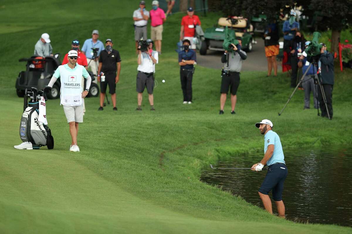 Dustin Johnson of the United States plays a shot as he stands in the water on the 15th hole during the final round of the Travelers Championship at TPC River Highlands on Sunday, June 28, 2020 in Cromwell, Connecticut. (Maddie Meyer/Getty Images/TNS)