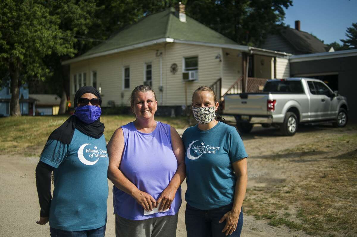 Umbareen Jamil, left, and Haley Lodhi, right, of the Islamic Center of Midland, pose for a photo Wednesday with Sanford resident Lori Brown, center, after Brown received a check for $500 from Reliable Plumbing and Heating to help fix her furnace, which was damaged in the flood. The business was too busy to help her, so they offered financial support. Brown lives across the street from Penny Tyler, whose childhood home was demolished earlier Wednesday, July 8, 2020 in preparation for a new home to be built free of cost thanks to Great Lakes Homes in Freeland. The Islamic Center of Midland and Midland Area Interfaith Friends will furnish the home. (Katy Kildee/kkildee@mdn.net)