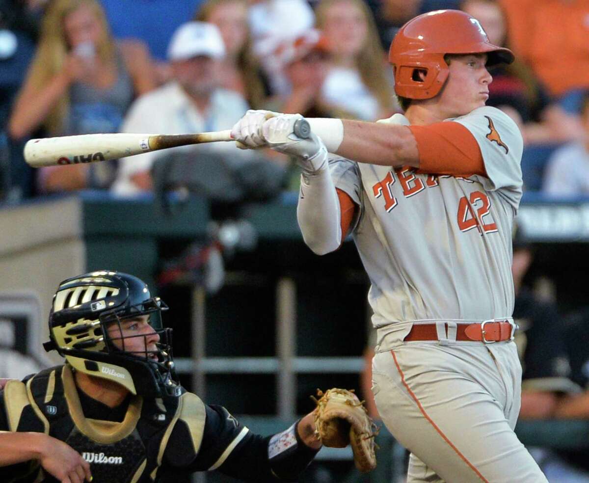 Texas' Kacy Clemens (42) follows through on a two-run single during the fourth inning of an NCAA baseball College World Series game in Omaha, Neb., Saturday, June 21, 2014. At left is Vanderbilt catcher Karl Ellison. (AP Photo/Ted Kirk)