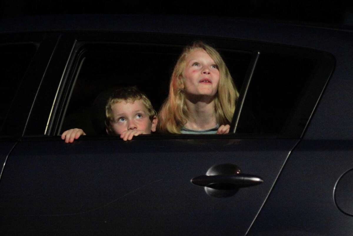 Sophia Cowell, 9 and her little brother Elvis 7, watch the July 4th holiday fireworks display at Veterans Memorial Park in Shelton, Conn., on Wednesday July 8, 2020. Due to the coronavirus pandemic, crowds weren't allowed to gather in the park, but were able to watch from the roads and homes nearby.