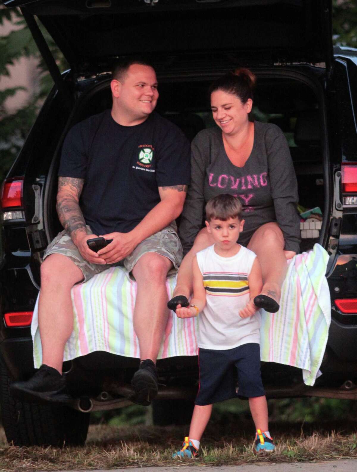 James McMahon, his wife Lynore, and son Logan, 5, wait for the start of the July 4th holiday fireworks display at Veterans Memorial Park in Shelton, Conn., on Wednesday July 8, 2020. Due to the coronavirus pandemic, crowds weren't allowed to gather in the park, but were able to watch from the roads and homes nearby.
