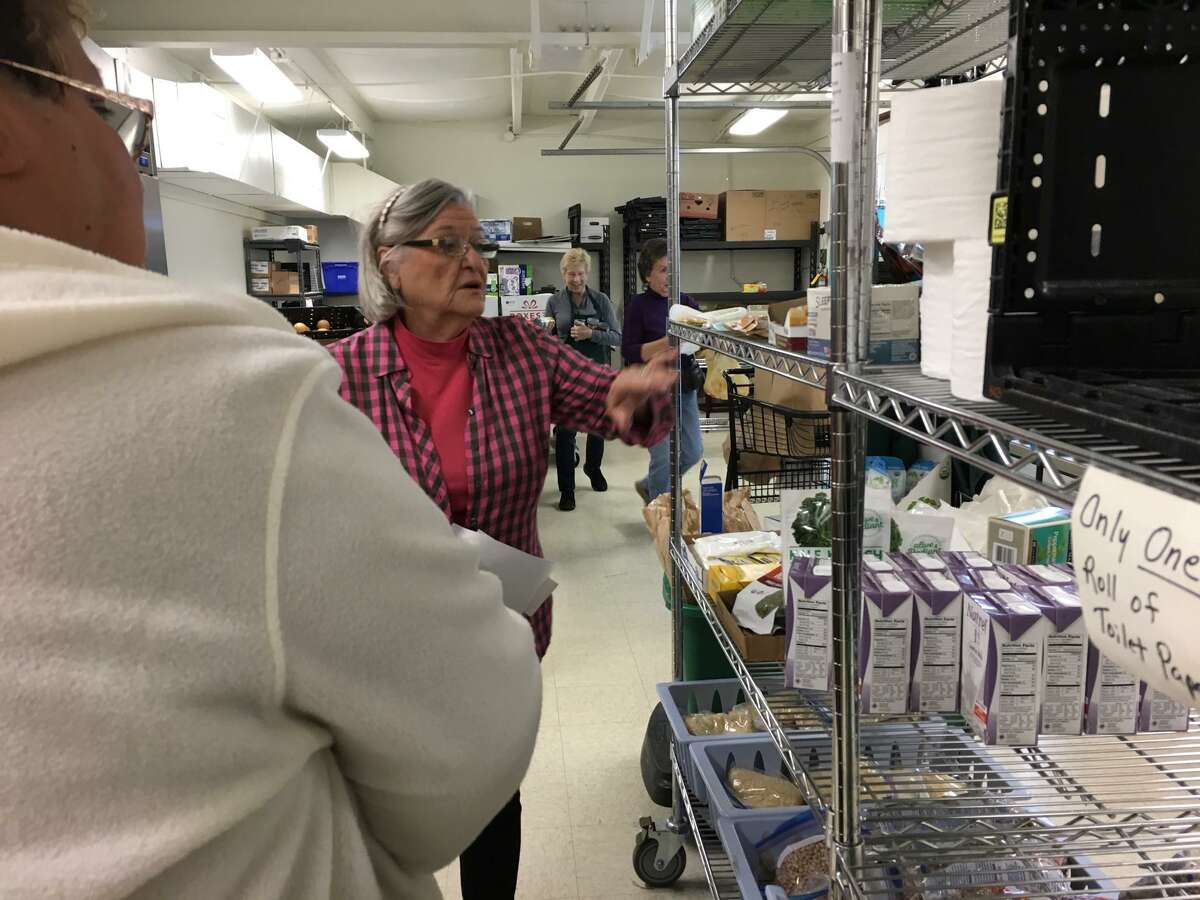 Mary White, director, East Spring Branch Food Pantry, helps a client shop Dec. 21. Pantry volunteers escort clients down the aisle as they shop. Clients are supposed to live in one of six ZIP codes in order to receive food. The amount of food a shopper can take home depends upon the size of the family.