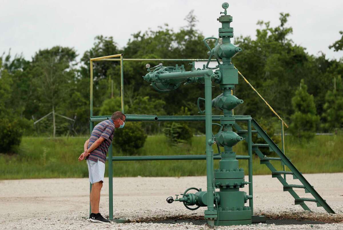 Jim Estes takes a closer look at a wellhead at an oil well located hundreds of feet behind his home on Monday, June 29, 2020, in League City, Texas.