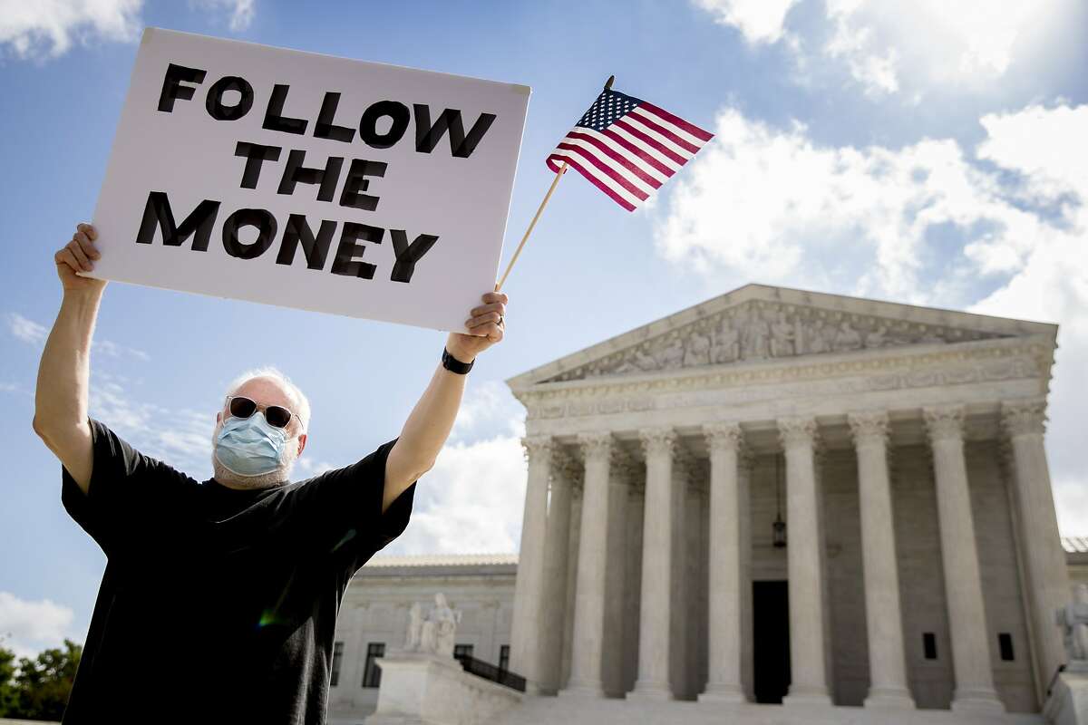 Bill Christeson holds up a sign that reads "Follow the Money" outside the Supreme Court, Thursday, July 9, 2020, in Washington. The Supreme Court ruled Thursday that the Manhattan district attorney can obtain Trump tax returns while not allowing Congress to get Trump tax and financial records, for now, returning the case to lower courts. (AP Photo/Andrew Harnik)